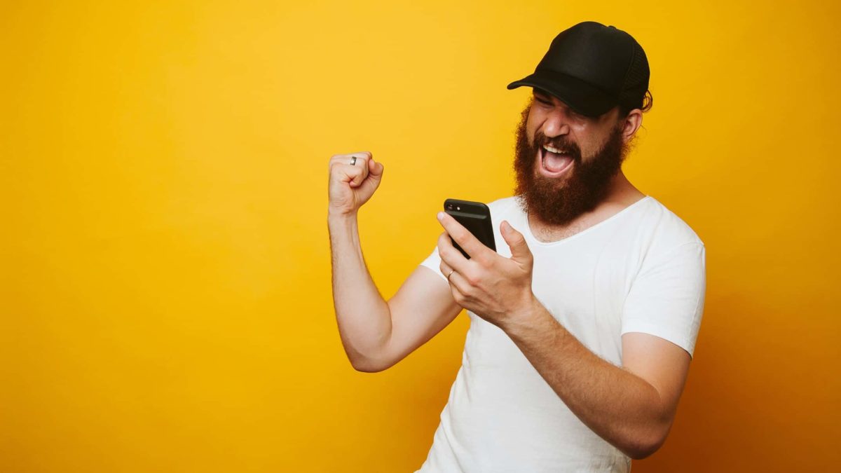 man looking at mobile phone and cheering representing surging asx share price