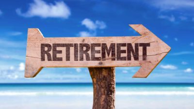 Wooden arrow sign stating 'retirement' against backdrop of beach