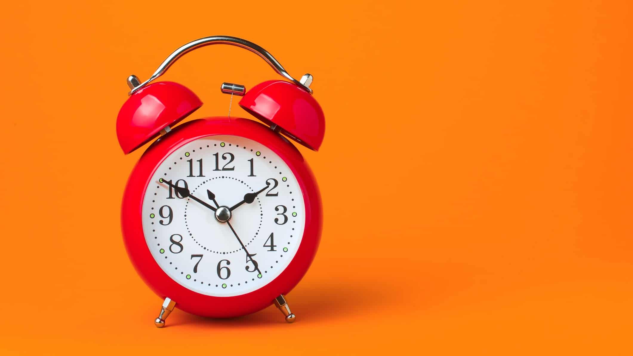 credit corp share price represented by red alarm clock against bright orange background