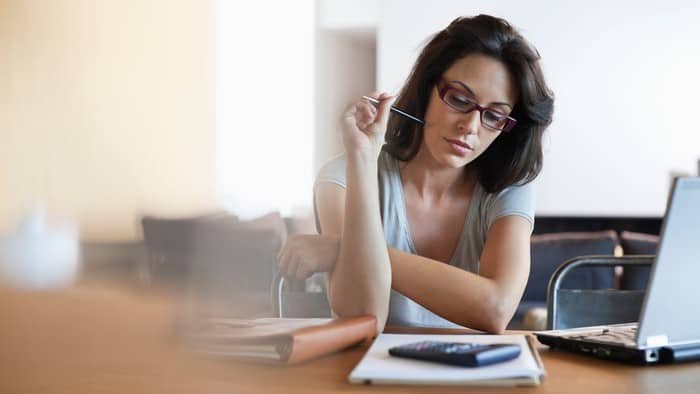 woman sitting at desk looking at calculator