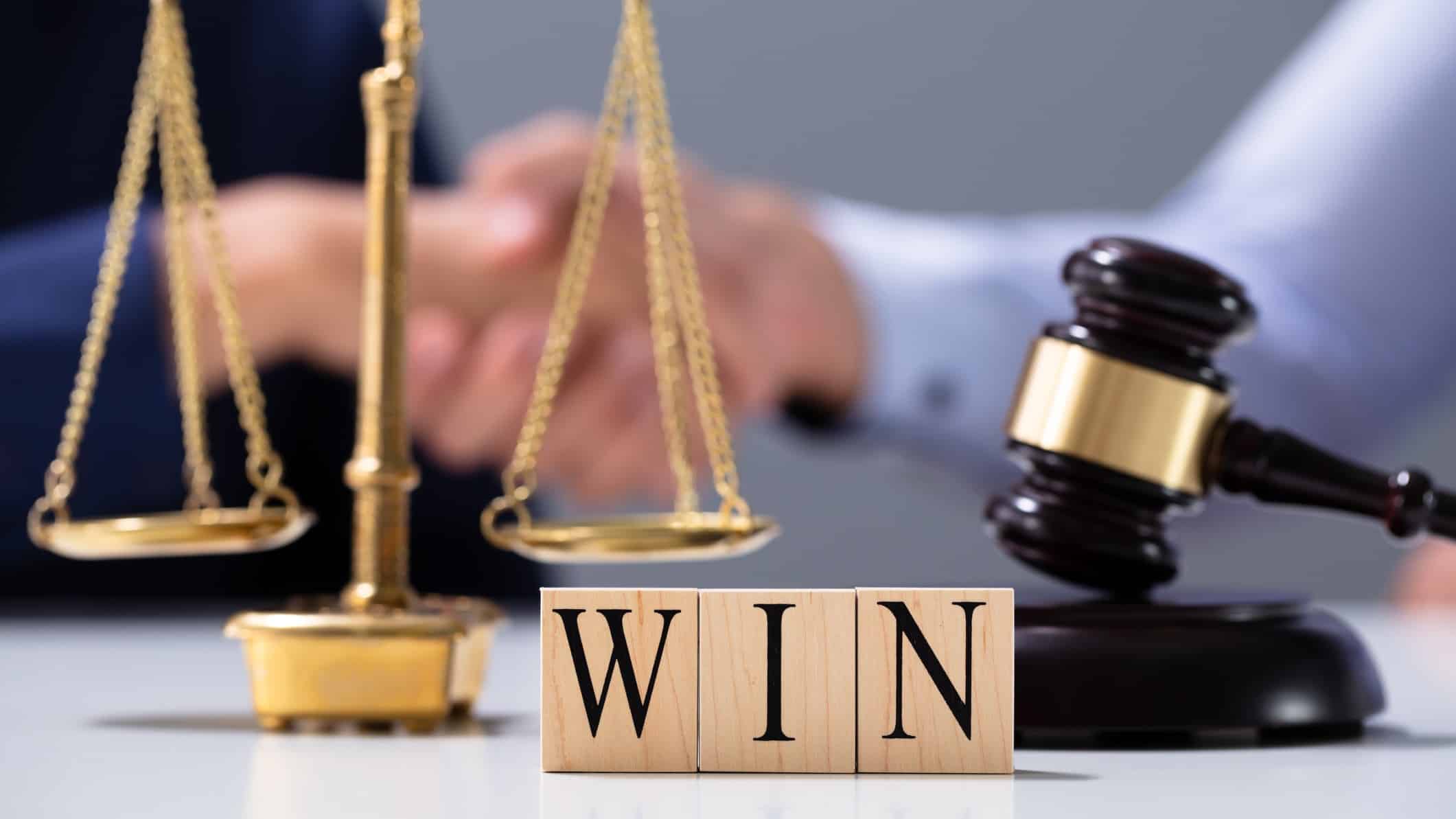 Woolworths win in court represented by scales, judges hammer and wooden blocks spelling the word win