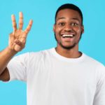 A man holds up his hand with 3 fingers up