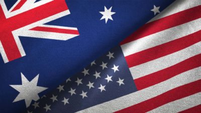 the australian flag lies alongside the united states flag on a flat surface.