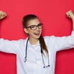 Young doctor raising arms in air with hands in fists celebrating a new development
