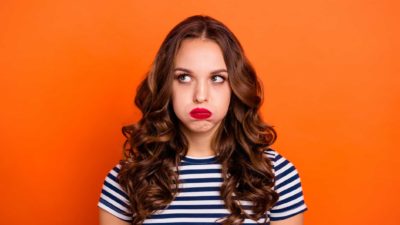 asx share price fall represented by lady in striped tshirt making sad face against orange background