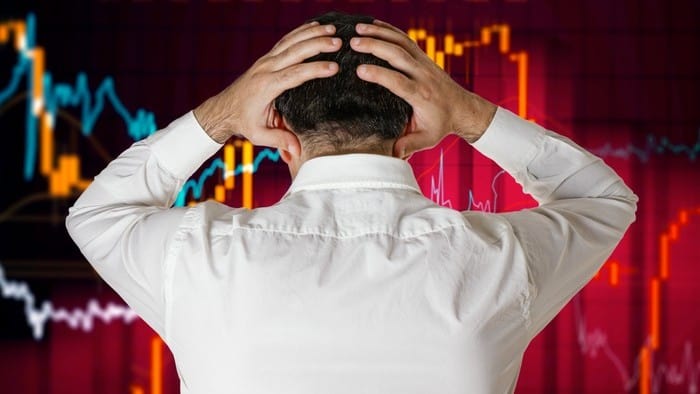 Man in front of chart holding his head as share market crashes
