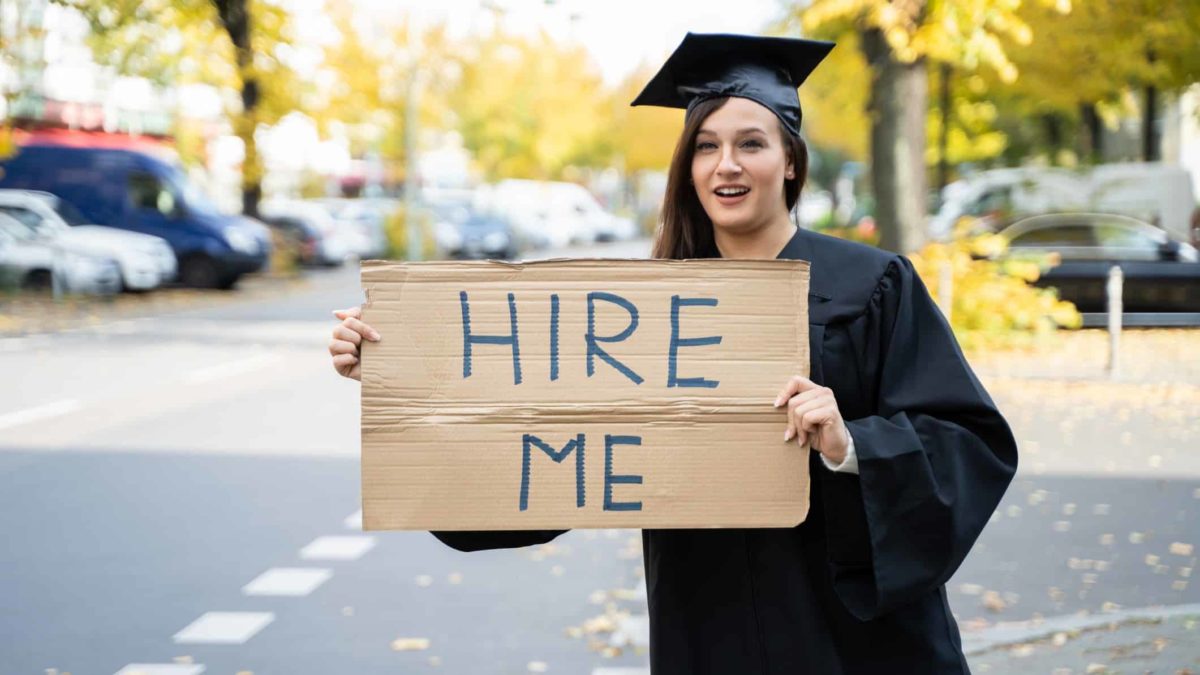 uni graduate holding sign that says hire me