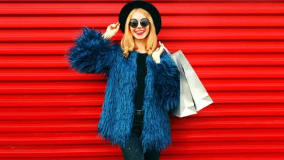 a fashionable young woman poses with a shopping bag.