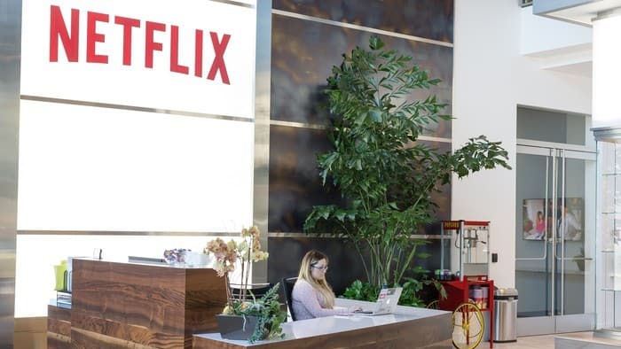 netflix stock represented by woman sitting behind reception desk at netflix office