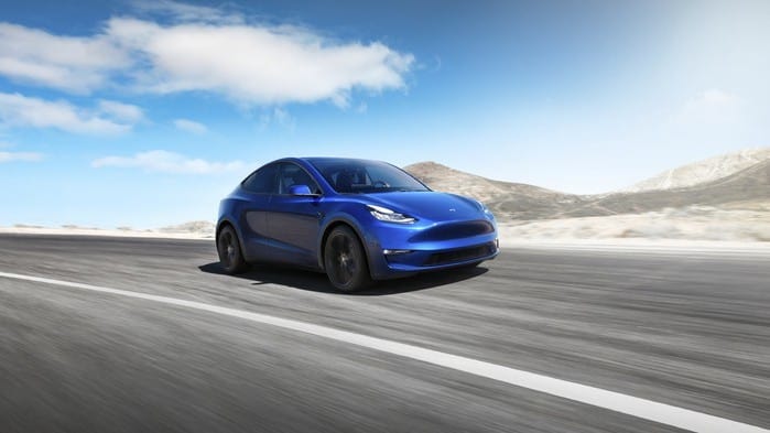 Tesla stock represented by tesla electric car driving along open road