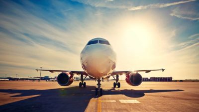 A large plane rolls down a runway with a sunny blue sky behind it as brokers reveal their outlook for the Flight Centre share price in FY23