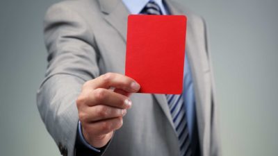Man in business attire holding up red card to denote a fine