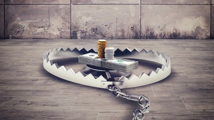 Cash piled up in the middle of a bear trap symbolising risky investments