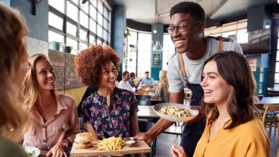 young man serving a group of customers at restaurant