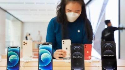 Falling Apple stock price represented by woman wearing face mask looking at products in Apple store