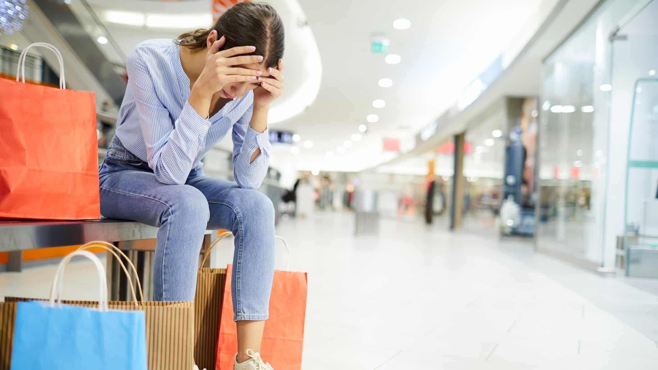 Falling ASX retail share price represented by sad shopper sitting in mall.