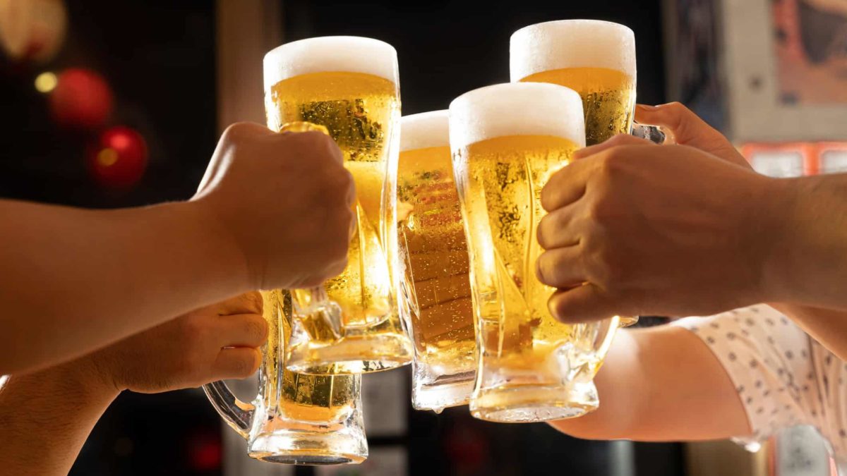 A group of arms raising beer glasses together in cheers
