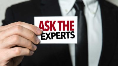 caucasian man in business suit holding sign that reads ask the experts