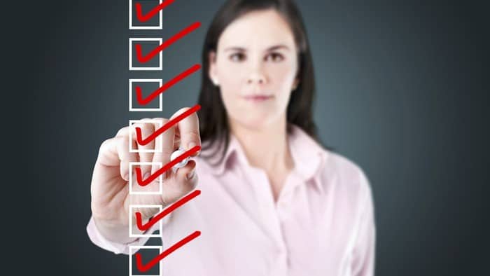 Woman in pink shirt ticks checklist with red checkmarks