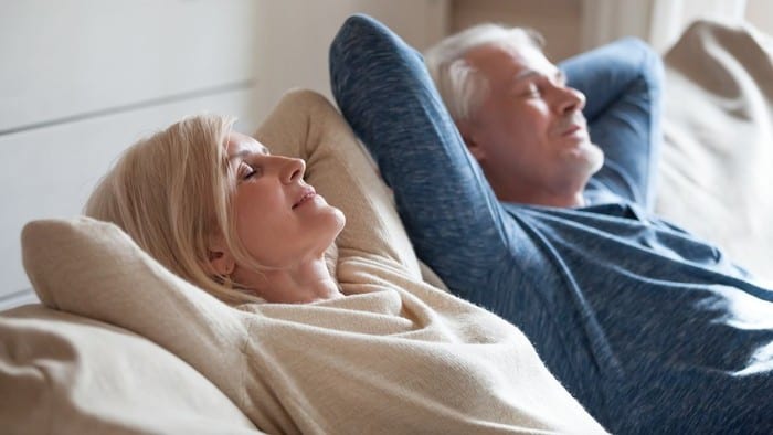 Retired couple reclining on couch with eyes closed