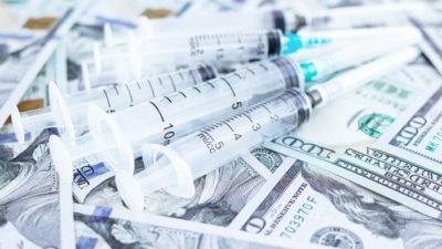 Vaccine vials sitting on top of a pile of US cash
