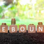 Wooden blocks spelling rebound with coins on top.