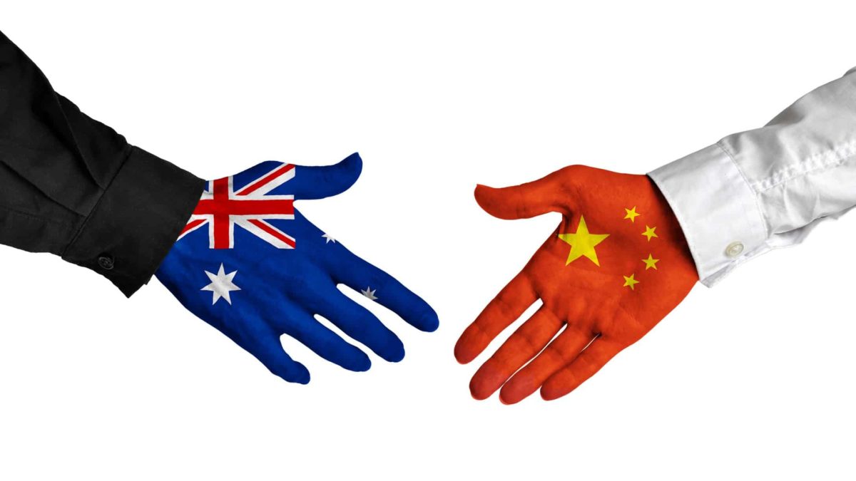 asx shares impacted by china represented by hands printed with australian and chinese flags shaking