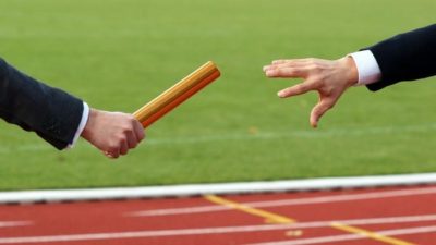 two businessmen pass the baton in a relay race, indicating a change or handover in an ASX share
