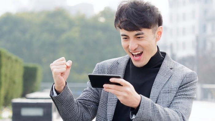 chinese man excitedly watching stocks on mobile phone