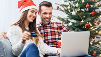 A happy man and woman on a computer at Christmas, indicating a positive trend for retail shares.