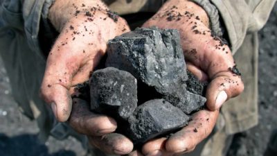 A miner holds two hands full of coal, indicating share price movement for coal and energy companies