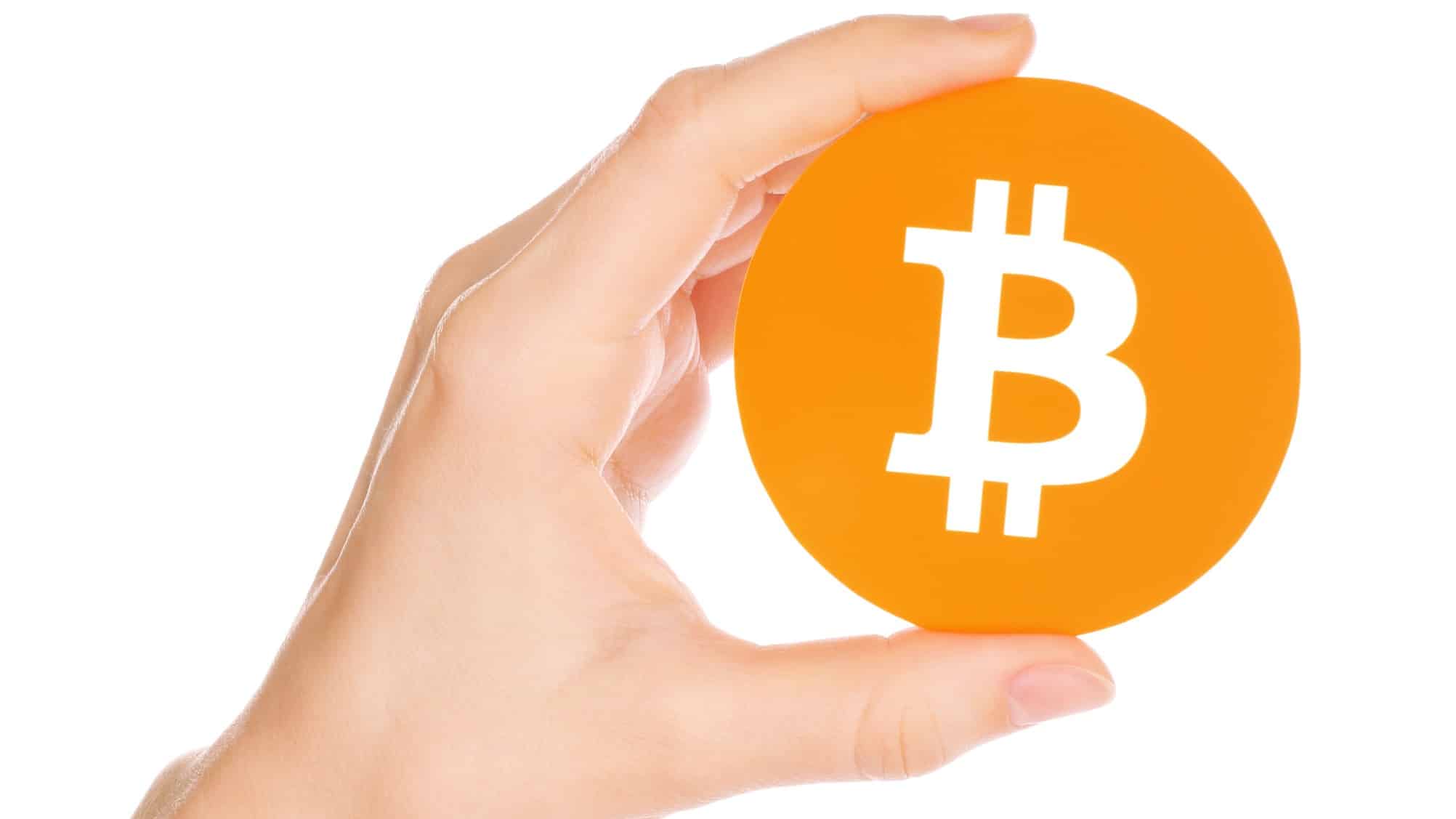 big orange cryptocurrency bitcoin being held up by hand