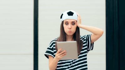 gambling asx share price fall represented by woman in soccer had looking frustrated at tablet screen