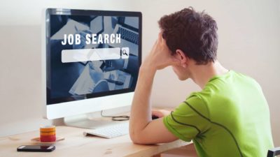 man attempting to seek for a job by looking at a computer screen that says job search