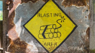 mining asx share price represented by yellow sign stating blasting area downgrade