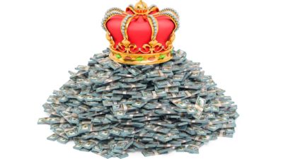 A crown sits on a pile of money, indicating the richest people