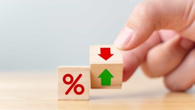 A hand moves a building block from green arrow to red, indicating negative interest rates