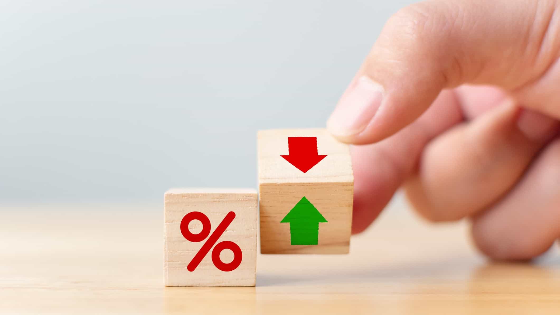 A hand moves a building block from green arrow to red, indicating negative interest rates