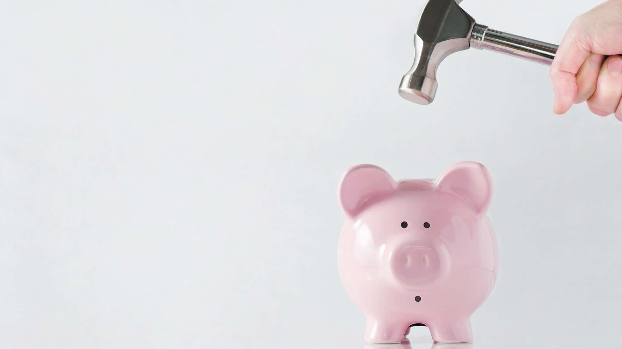 A scared piggy bank braces as a hammer comes down, indicating a poor decision to split company