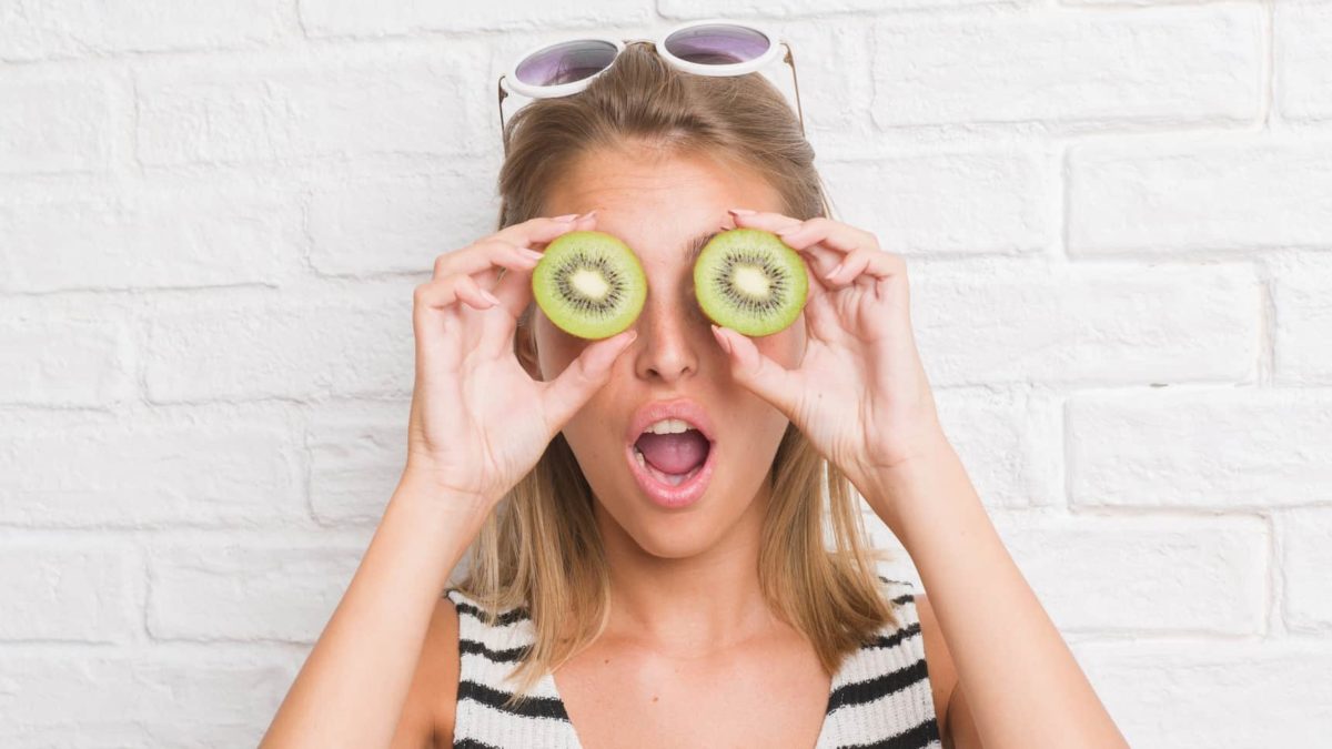 A women looking surprised with kiwifruit slices on her eyes, indicating share price movement for farming and produce shares