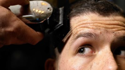 man looking up as if watching asx share price whilst using electric shaver