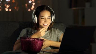 streaming stocks such as Netflix represented by happy woman watching tv