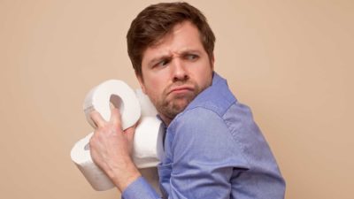 toilet paper asx share price represented by man clutching rolls of toilet paper close to his chest