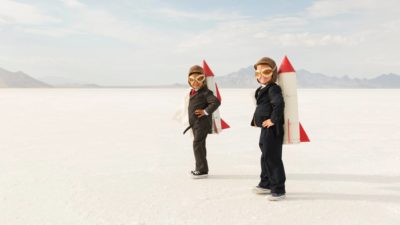 Two boys with cardboard rockets strapped to their backs, indicating two ASX companies with rocketing share prices