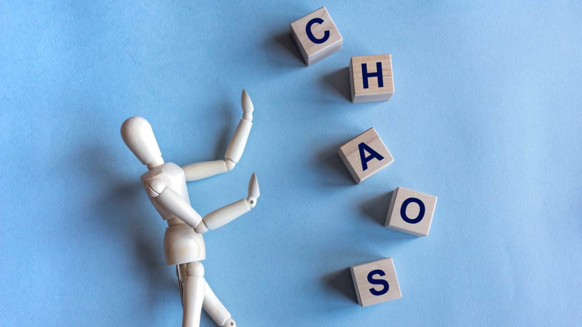 Wooden blocks spelling out 'Chaos' next to a wooden figurine