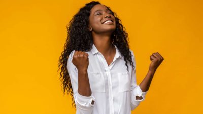 A happy woman raises her face in celebration, indicating positive share price movement on the ASX