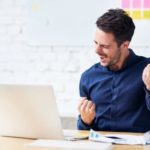 Investor happily looking at rising share price on laptop.