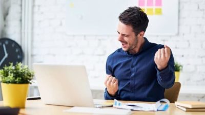 Investor happily looking at rising share price on laptop