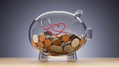 Glass piggy bank with coins and stethoscope in shape of a heart inside
