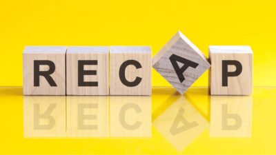 Wooden block letters spelling 'Recap' on a yellow background